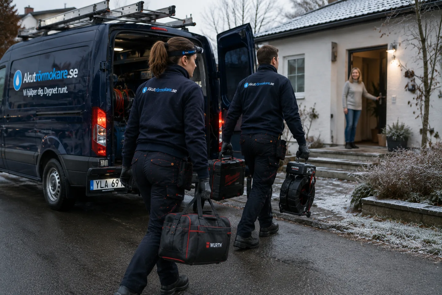 Två rörmokare anländer till ett hus i vinterlandskap och möts av kunden i dörren.